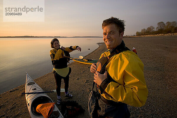 A couple prepares to kayak in the ocean.