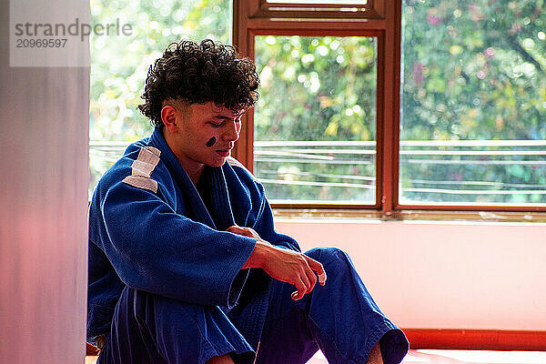 Judo fighter portrait resting in dojo with some trees at background