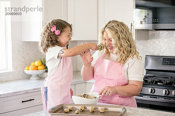 Daughter feeding mom some cookie dough in the kitchen