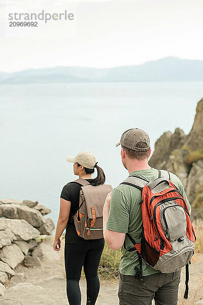 Close up of backpack with couple overlooking water