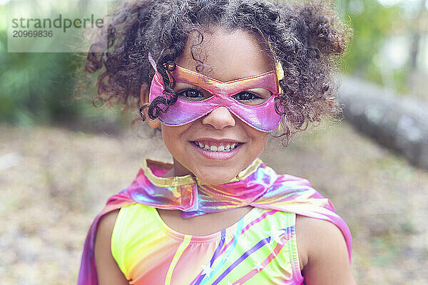 Close-up of a smiling young girl in a superhero mask and costume