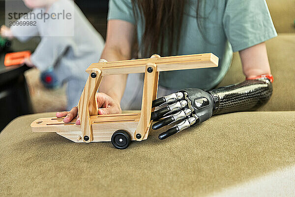 Young woman holding baby toy using prosthesis