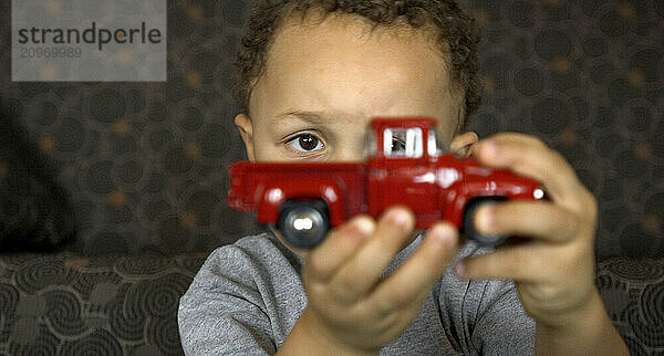 A boy holds a red toy truck.