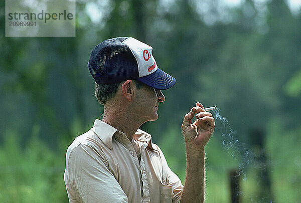 With a cap and a cigarette a man relaxes.