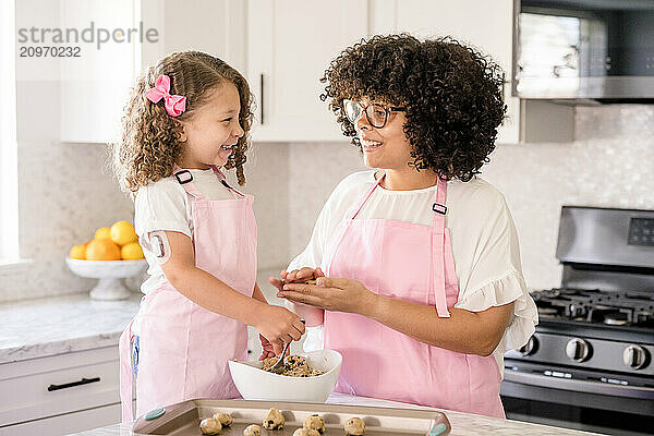 Biracial Sisters laughing and making cookies together in the kitchen