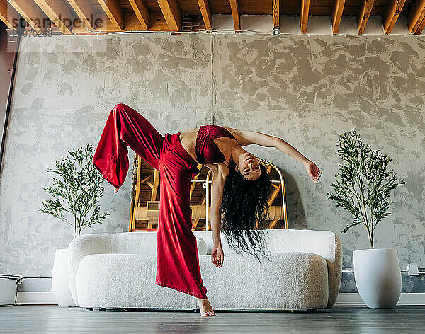 Woman dancing energetically in a loft with red outfit