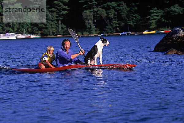 Man  boy and dog paddle kayak on Kezar Lake  Maine.