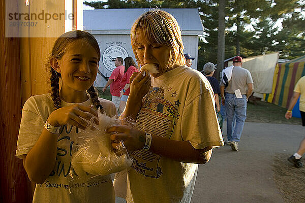 Two girls enjoy maple sugar cotton candy at the Fryeburg Fair in Maine.