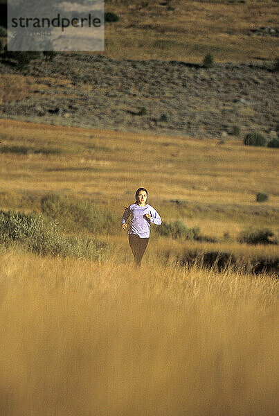 Young woman running along the West Fork of the Carson River in in Hope Valley  CA.