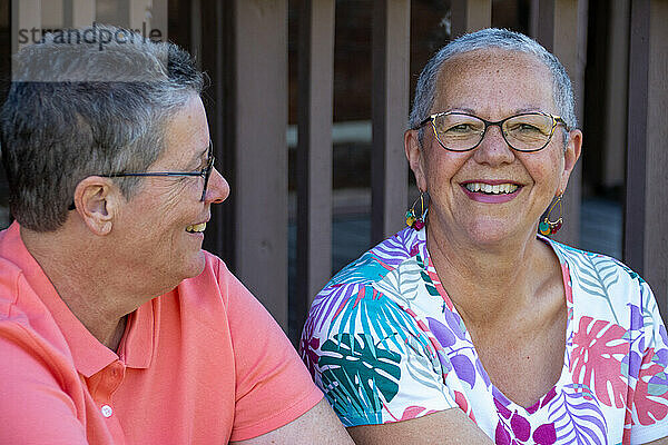 Older gay couple sitting and smiling together outdoors