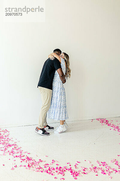 Couple hugging in a room with pink flower petals on the floor