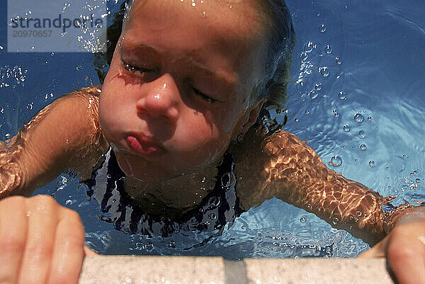 Close-up of young girl emerging from a swimming pool.