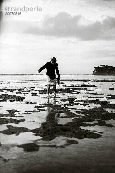 A young man walks along the beach in Bali.