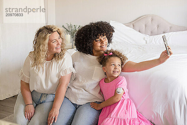 Daughters are taking a selfie with mom in the bedroom