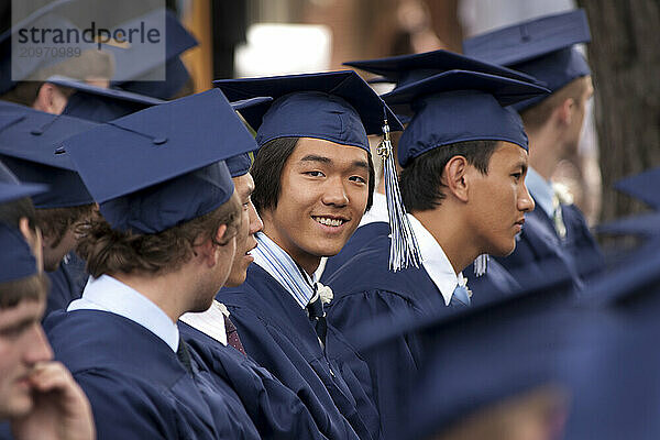 Seated students in caps and gowns at a high school graduation ceremony.