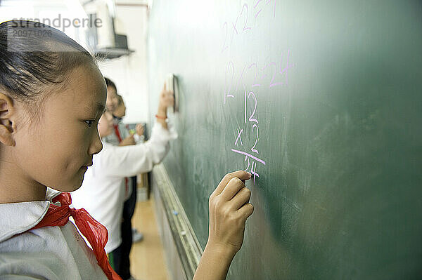 Young students practicing math on a chalkboard.