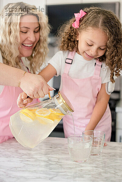 Close up of lemonade being poured into glasses by mother and daughter