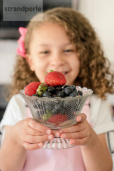 Close up of little girls hands holding a bowl of berries