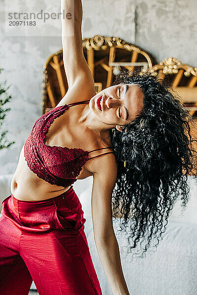 Woman joyfully dancing in a red outfit indoors