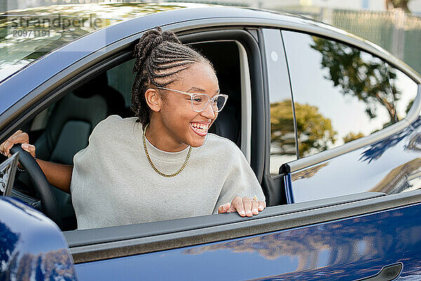 Young driver getting out of a car laughing