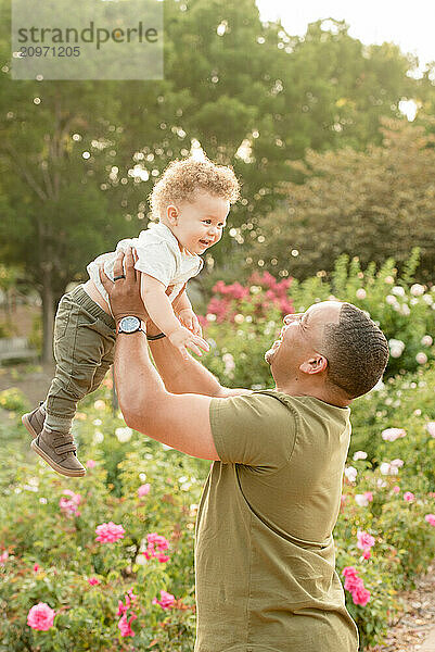 Father lifting son in the air in garden