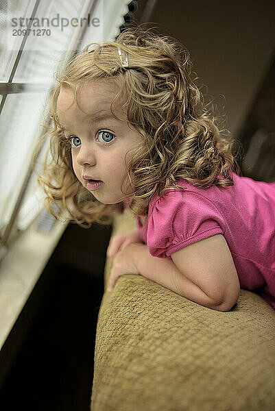 Profile beautiful toddler blonde curls watching out window