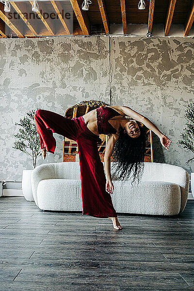 Woman dancing energetically in a loft with red outfit