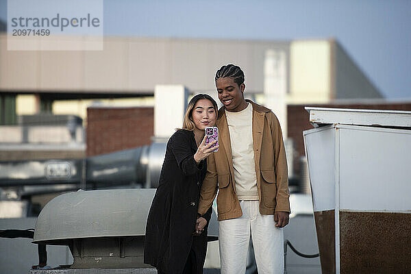 Multi racial couple taking a selfie on a roof-top urban setting