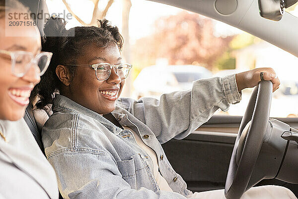 Young lady laughing behind the steering wheel of a car