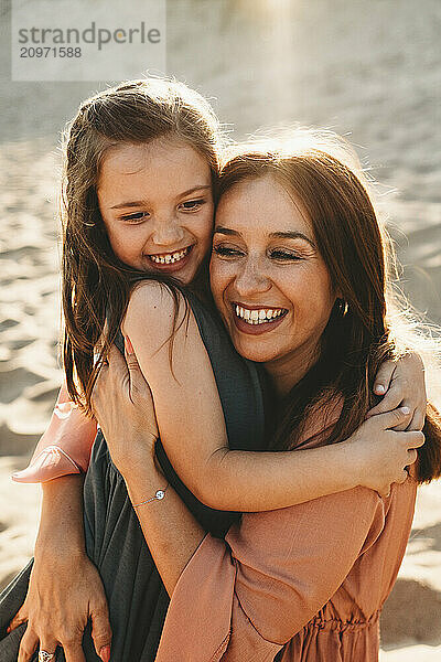 Spanish Happy mother and daughter laughing hugging smiling at beach