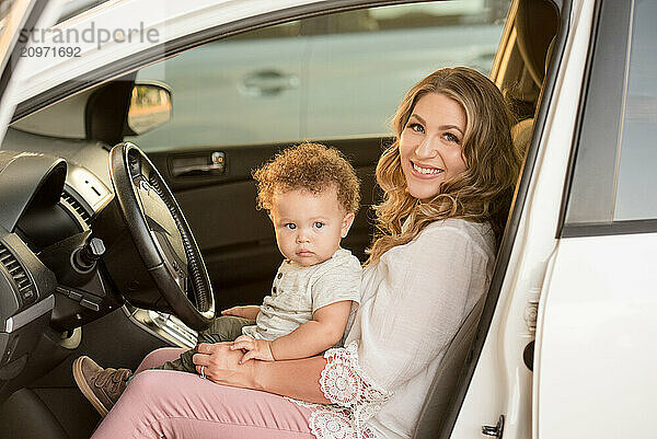 Mother and son sitting in drivers seat of car