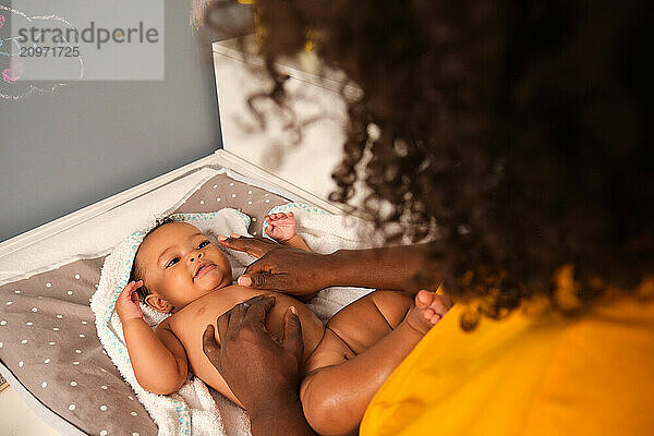 Mother applying baby lotion after bath time in nursery