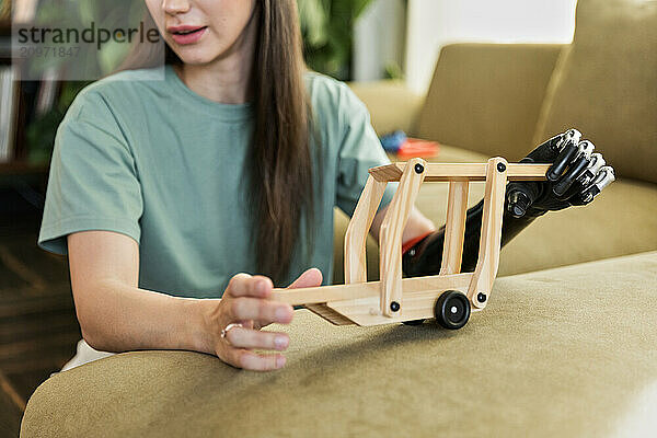 Young woman holding baby toy using prosthesis