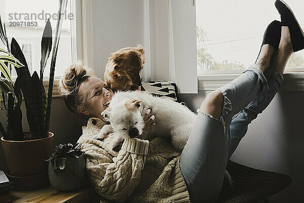 Woman playing with two rescue dogs in a cozy indoor setting.