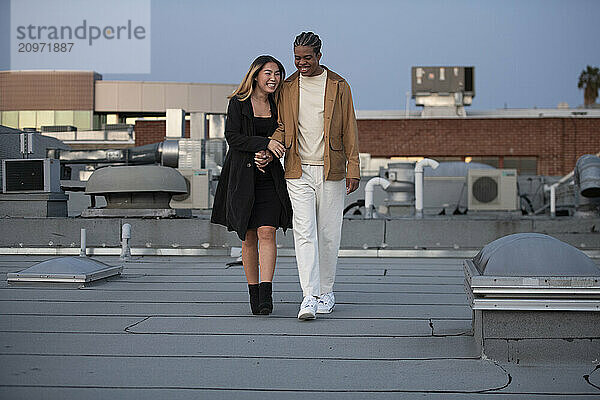 Multi racial couple walking and flirting on a downtown urban roo