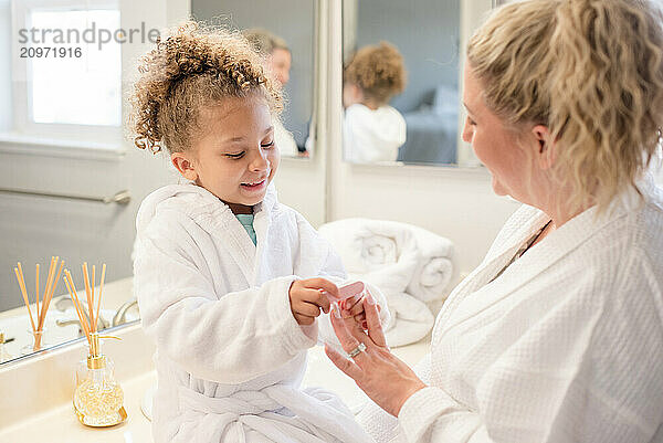 Mother and daughter are wearing robes in the bathroom