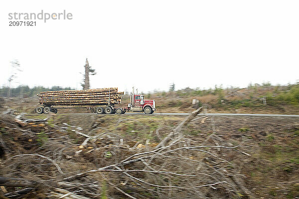 Log truck driving timber to mill through clear cuts in Oregon.