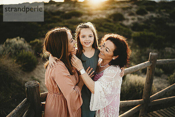 Three generations hugging women mom grandma girl beach sunset Spain