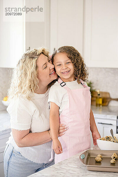 Mother and daughter smiling in the kitchen with mom holding daughter