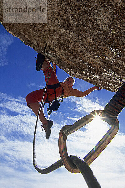 Woman climbing above protection  Joshua Tree National Park  California (back lit)