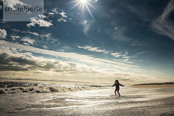 Young girl playing in waves under beautiful sunny sky