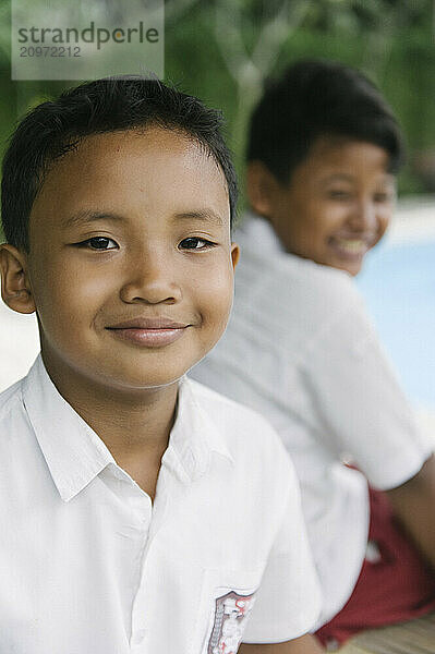 A group of young boys smiling and playing on an open field and climbing a tree