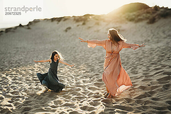 Mother and daughter twirling dancing beach sunset dresses