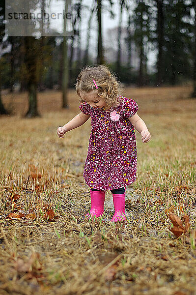 Happy toddler splashing in puddles pink boots