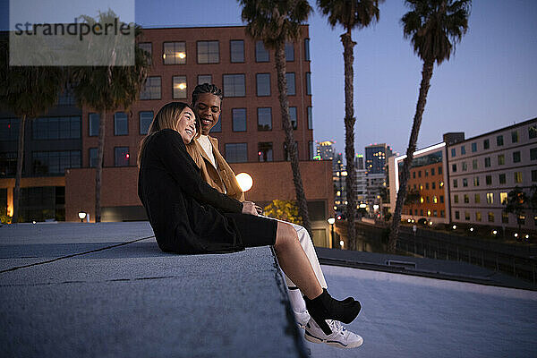 Asian woman and black boyfriend sharing laugh at dusk on downto