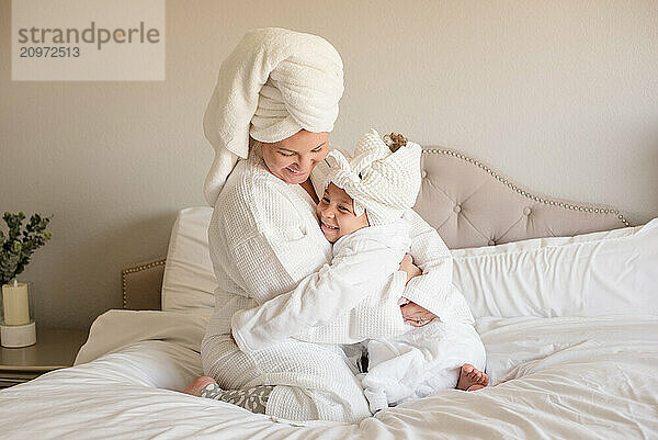 Mother and daughter giving each other a hug wearing white robes