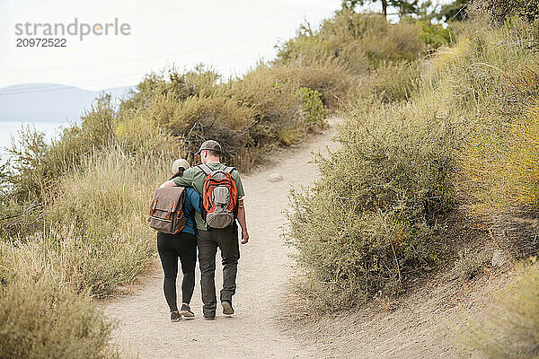 Hiker couple holding each other while walking on a trail