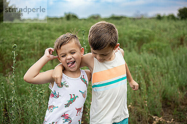 two boys in green field smiling and making goofy face