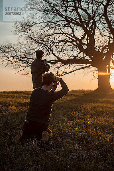 Two photographers take pictures of nature at sunset.