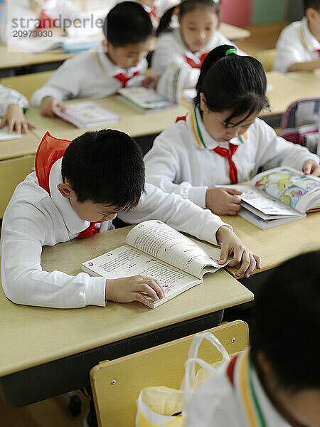 A classroom of young students reading a lesson from their textbook.